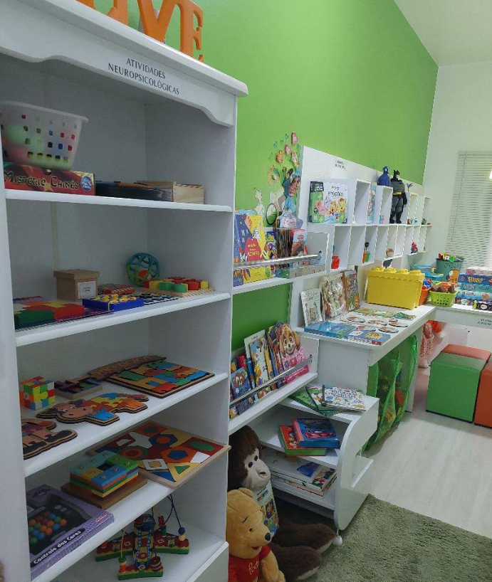 Sala infantil com estantes de jogos, quebra-cabeças e materiais de atividades neuropsicológicas